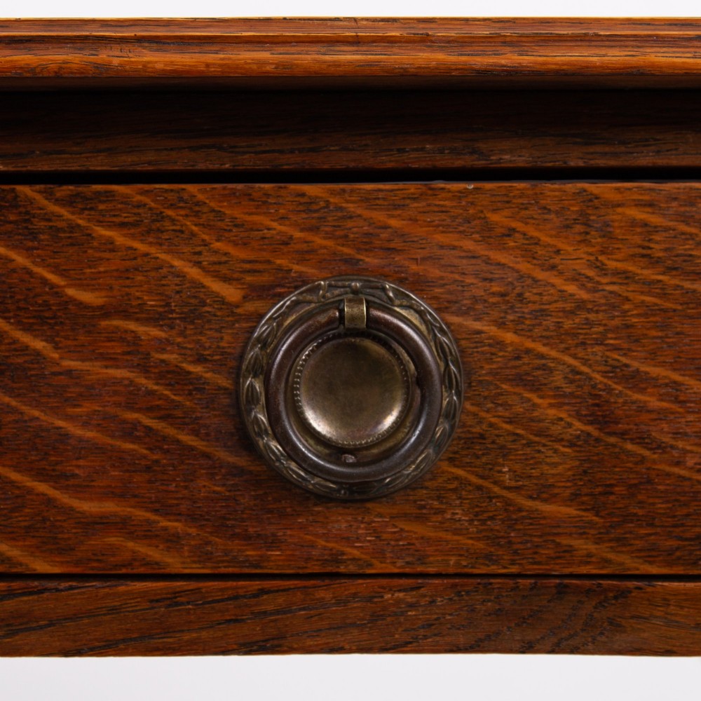 An antique dark oak side table featuring a single drawer with a brass drop ring pull, slender turned legs, and a bobbin stretcher base. View VII