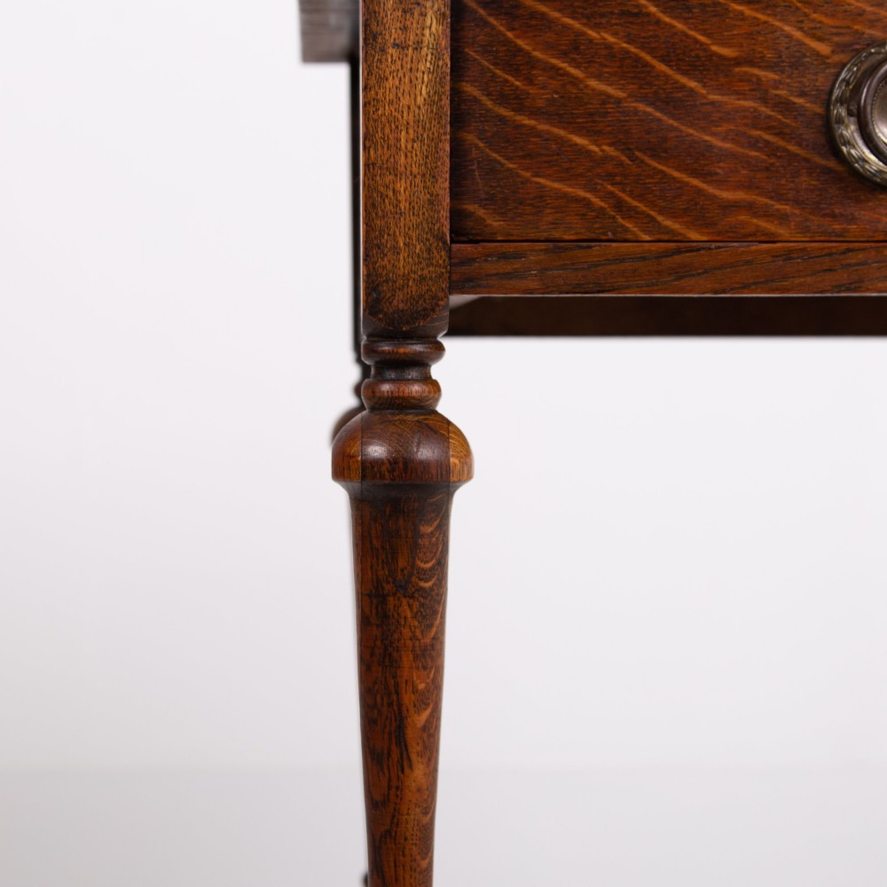 An antique dark oak side table featuring a single drawer with a brass drop ring pull, slender turned legs, and a bobbin stretcher base. View IX