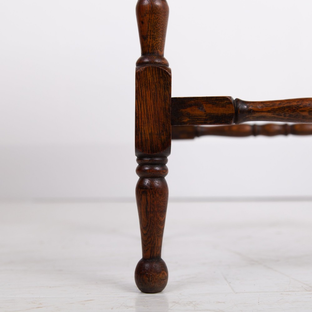 An antique dark oak side table featuring a single drawer with a brass drop ring pull, slender turned legs, and a bobbin stretcher base. View XI