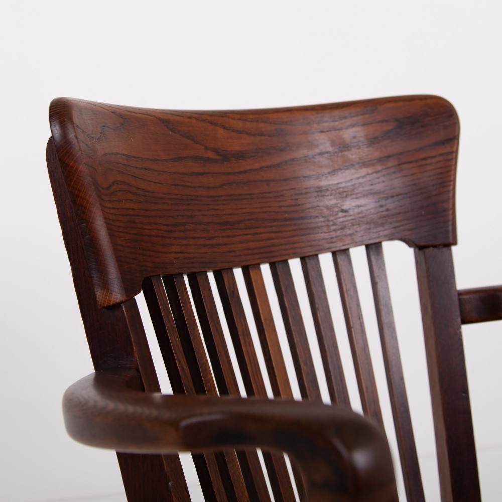 An Edwardian dark oak desk chair featuring a vertical slat backrest, curved armrests, and a studded leather seat. View VII
