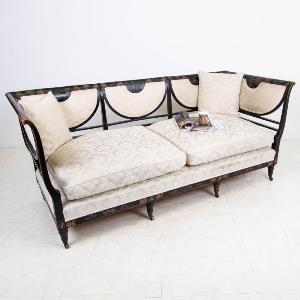 A Victorian Chinoiserie sofa with a black lacquered frame featuring gilt painted details, semicircular cream patterned back panels, and cream upholstered seat cushions. View II
