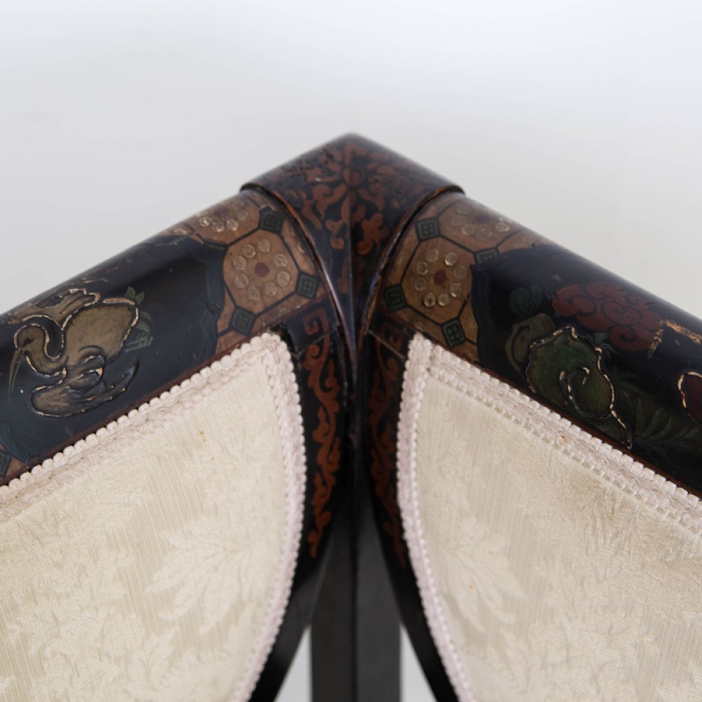 A Victorian Chinoiserie sofa with a black lacquered frame featuring gilt painted details, semicircular cream patterned back panels, and cream upholstered seat cushions. View VI