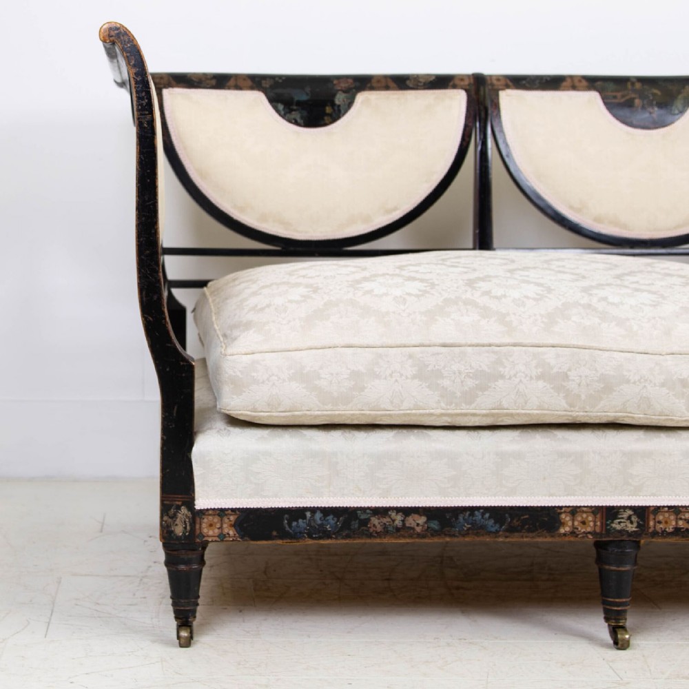 A Victorian Chinoiserie sofa with a black lacquered frame featuring gilt painted details, semicircular cream patterned back panels, and cream upholstered seat cushions. View VII