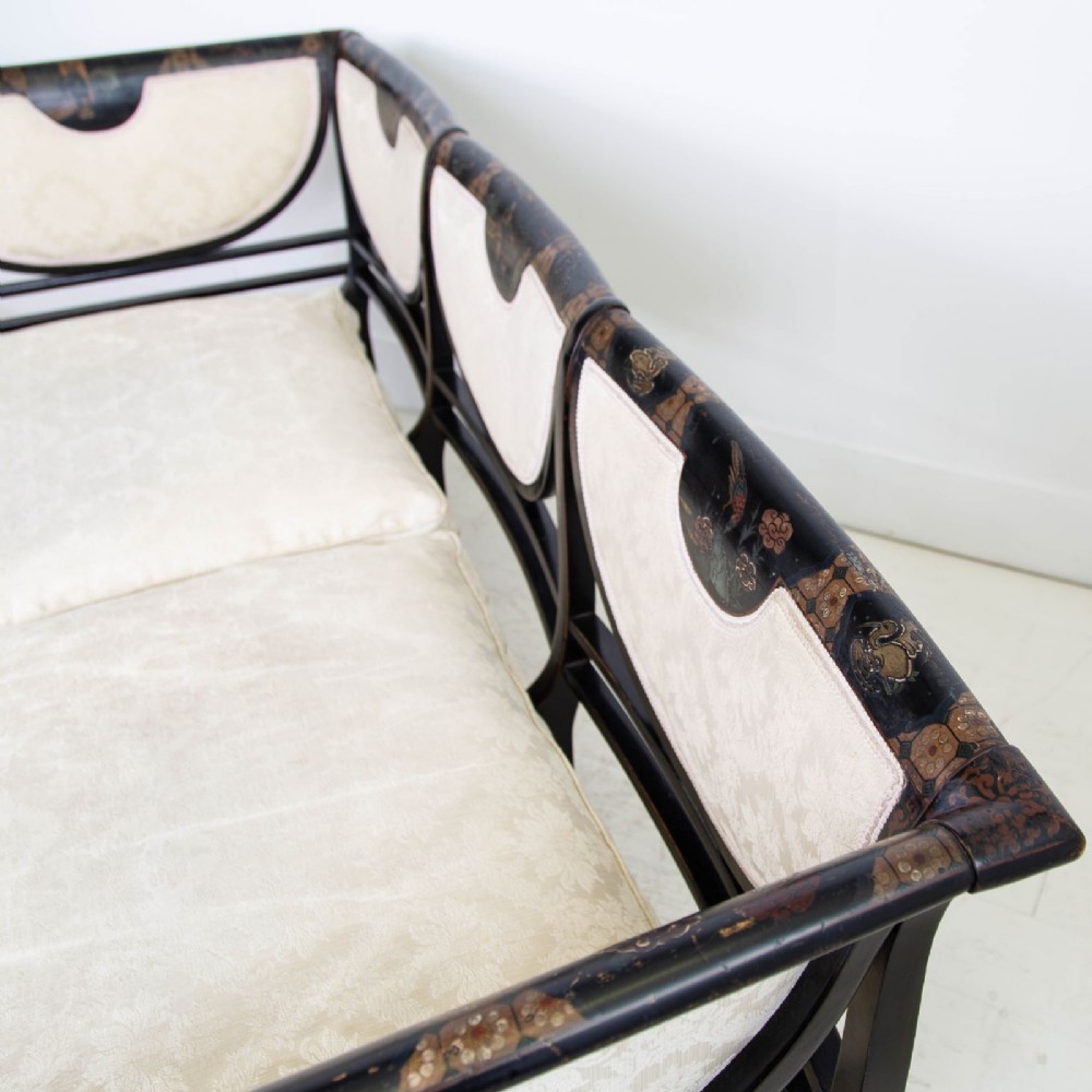 A Victorian Chinoiserie sofa with a black lacquered frame featuring gilt painted details, semicircular cream patterned back panels, and cream upholstered seat cushions. View VIII
