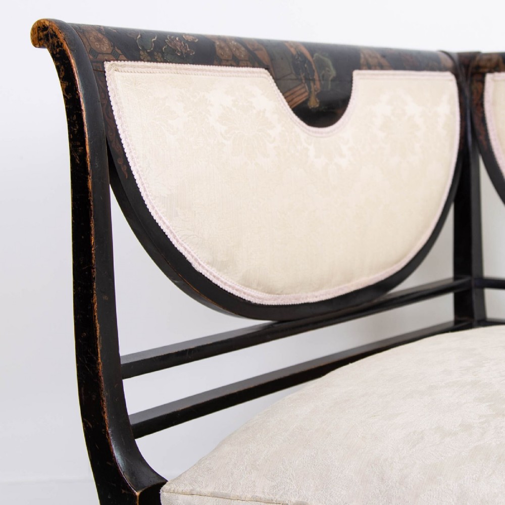 A Victorian Chinoiserie sofa with a black lacquered frame featuring gilt painted details, semicircular cream patterned back panels, and cream upholstered seat cushions. View IX