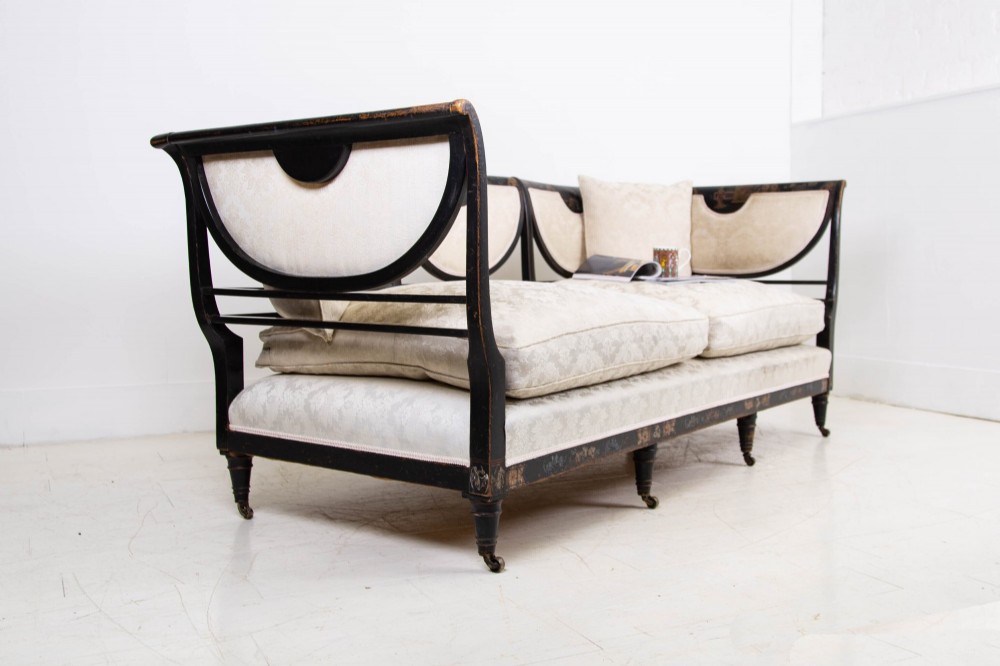 A Victorian Chinoiserie sofa with a black lacquered frame featuring gilt painted details, semicircular cream patterned back panels, and cream upholstered seat cushions. View XIV