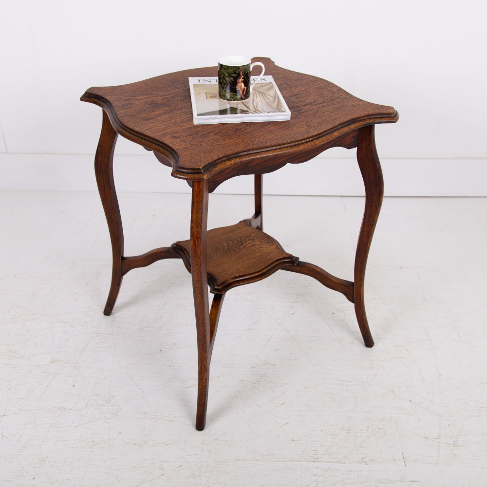 An Edwardian oak occasional table featuring a serpentine-shaped top surface, four slender cabriole legs, and a matching lower shelf. View II