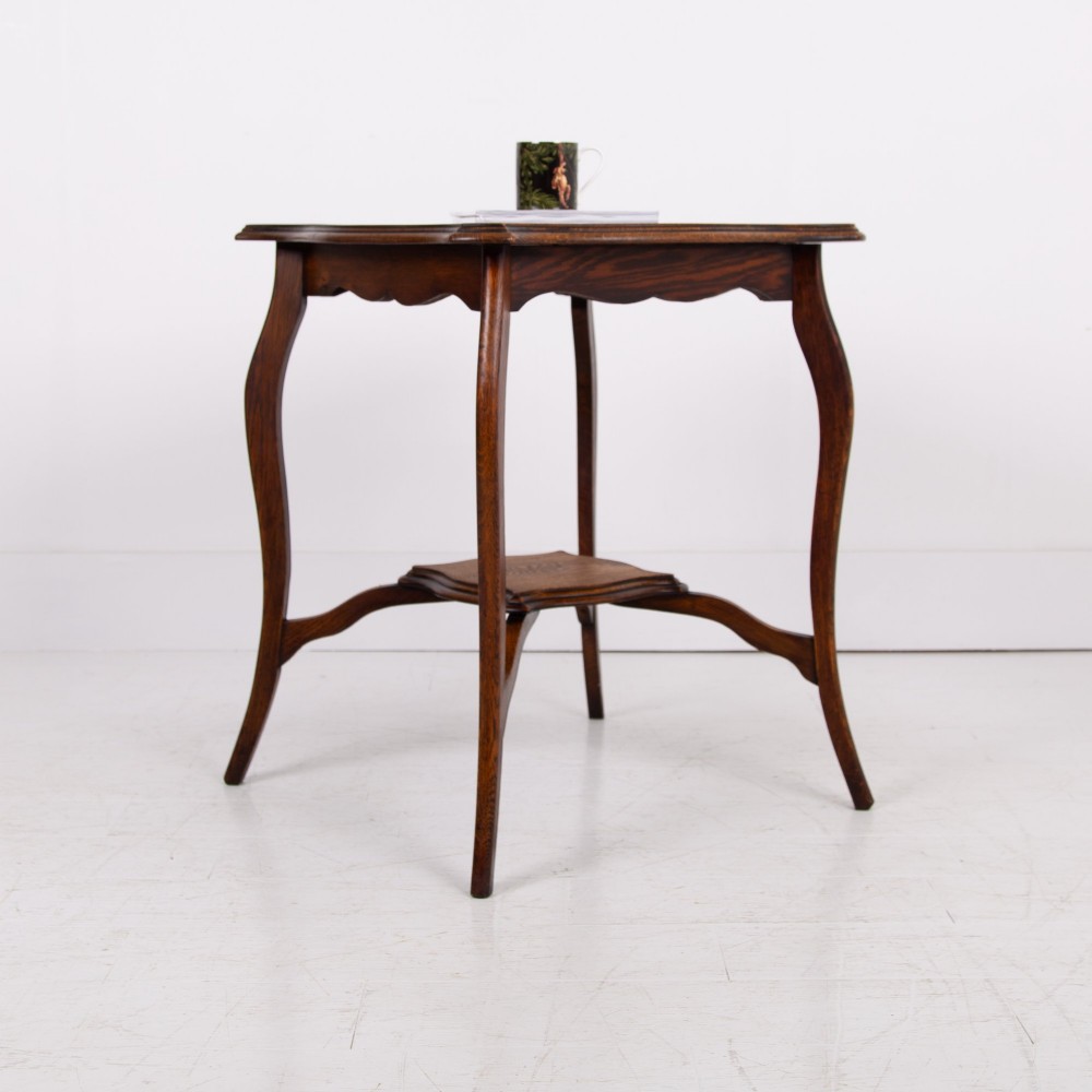 An Edwardian oak occasional table featuring a serpentine-shaped top surface, four slender cabriole legs, and a matching lower shelf. View III