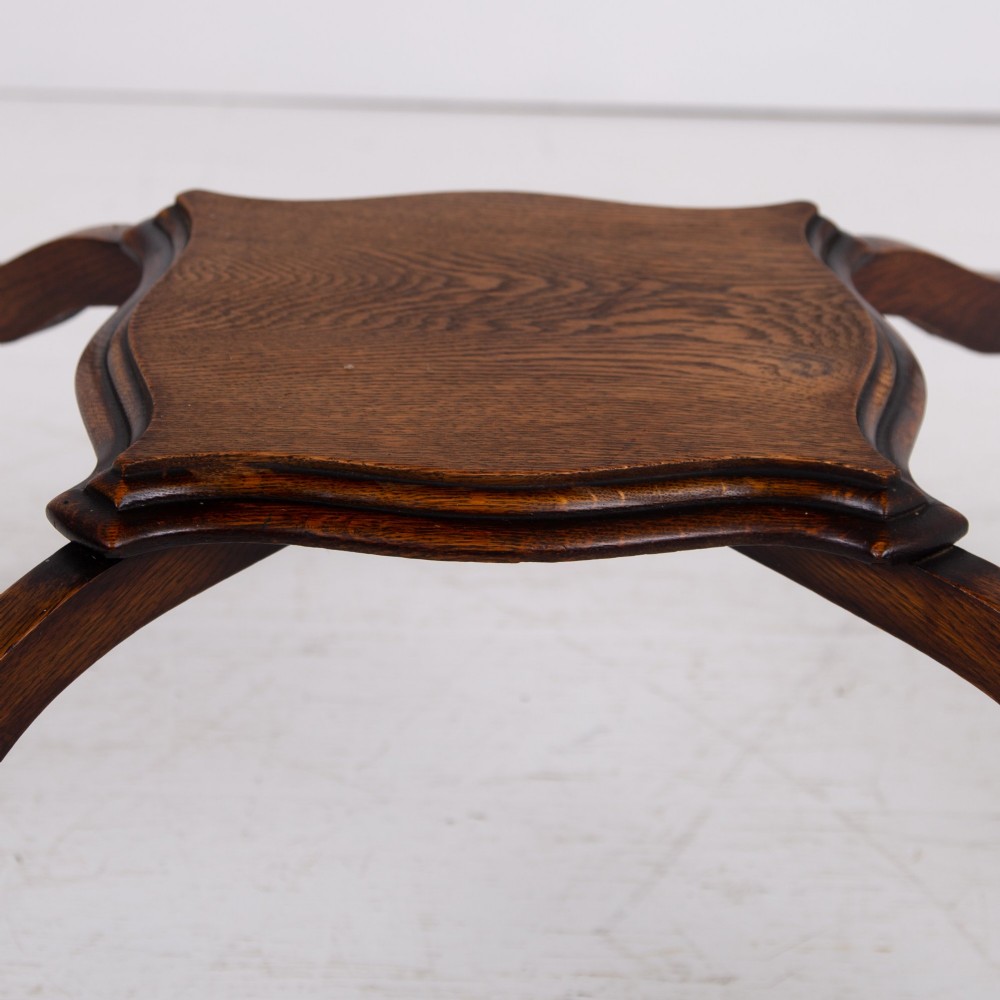 An Edwardian oak occasional table featuring a serpentine-shaped top surface, four slender cabriole legs, and a matching lower shelf. View V