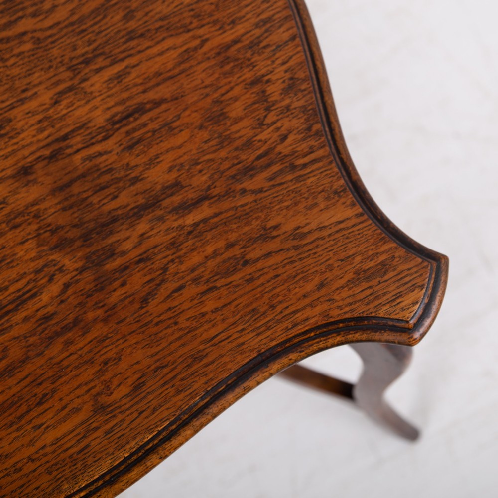 An Edwardian oak occasional table featuring a serpentine-shaped top surface, four slender cabriole legs, and a matching lower shelf. View VIII