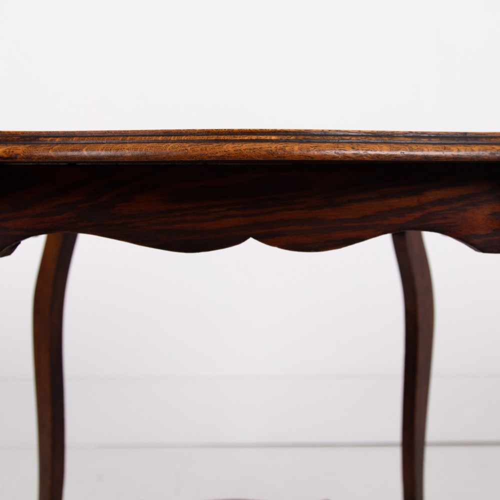An Edwardian oak occasional table featuring a serpentine-shaped top surface, four slender cabriole legs, and a matching lower shelf. View IX