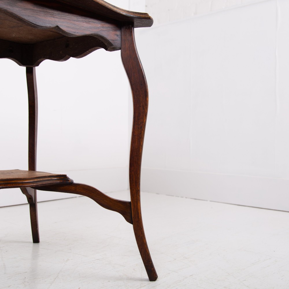 An Edwardian oak occasional table featuring a serpentine-shaped top surface, four slender cabriole legs, and a matching lower shelf. View XI
