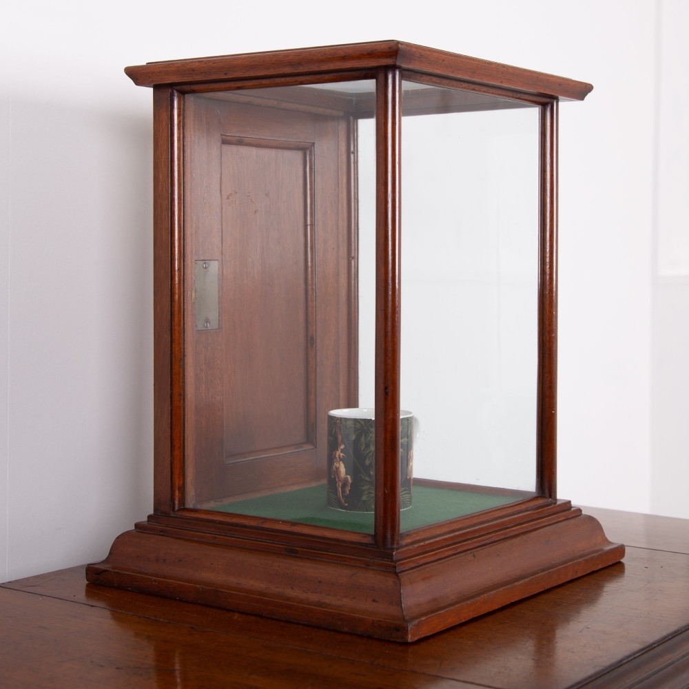 A vertical glazed tabletop display cabinet crafted from warm brown mahogany with glass side panels, turned columns, and a green felt-lined base. View II