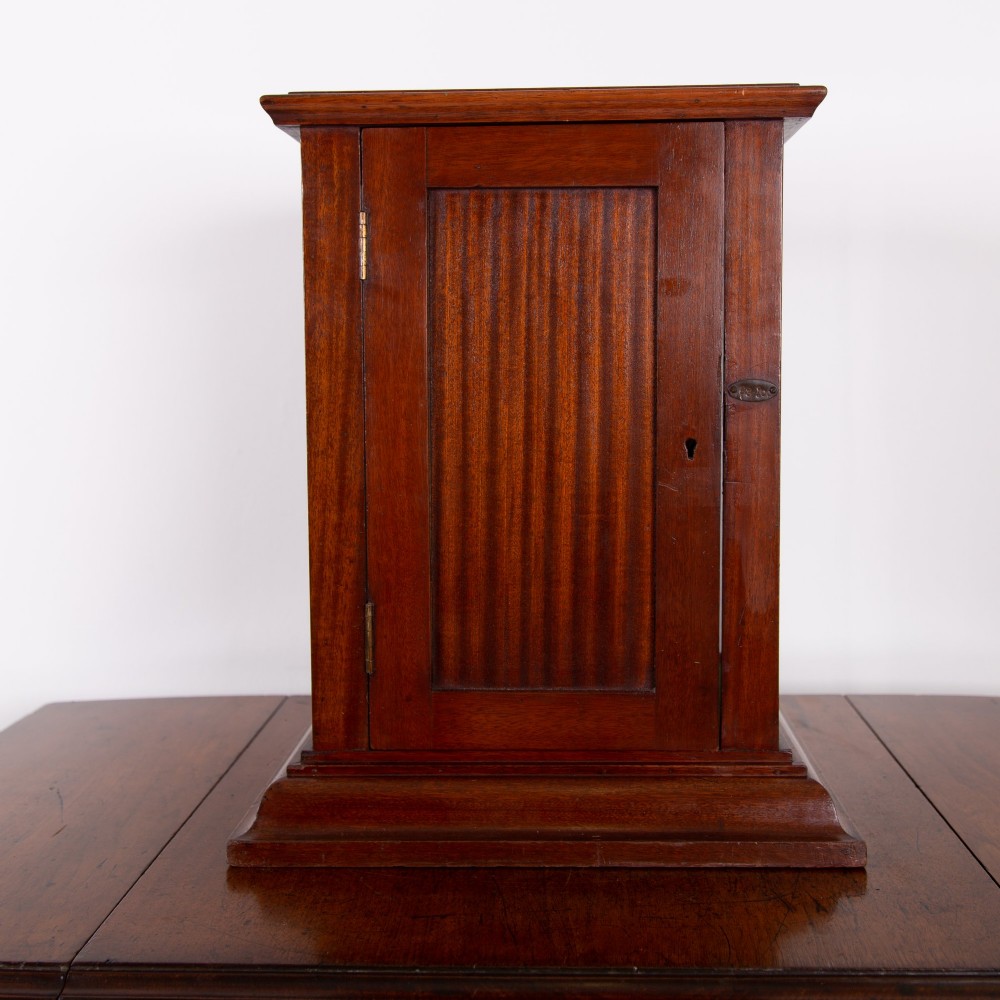 A vertical glazed tabletop display cabinet crafted from warm brown mahogany with glass side panels, turned columns, and a green felt-lined base. View IX