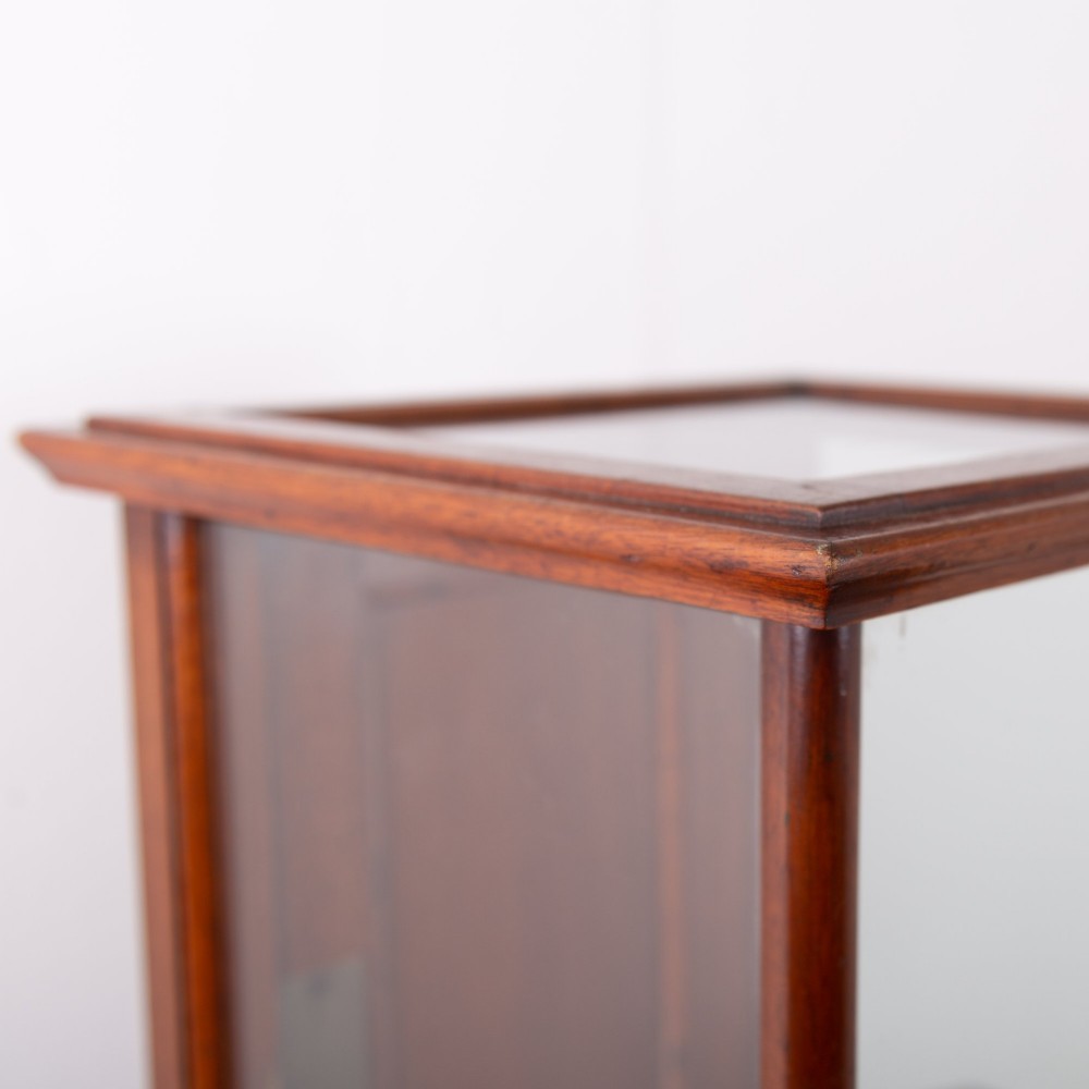 A vertical glazed tabletop display cabinet crafted from warm brown mahogany with glass side panels, turned columns, and a green felt-lined base. View X