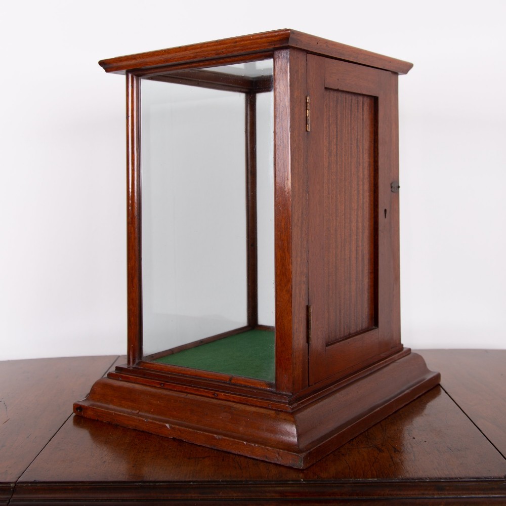 A vertical glazed tabletop display cabinet crafted from warm brown mahogany with glass side panels, turned columns, and a green felt-lined base. View XI