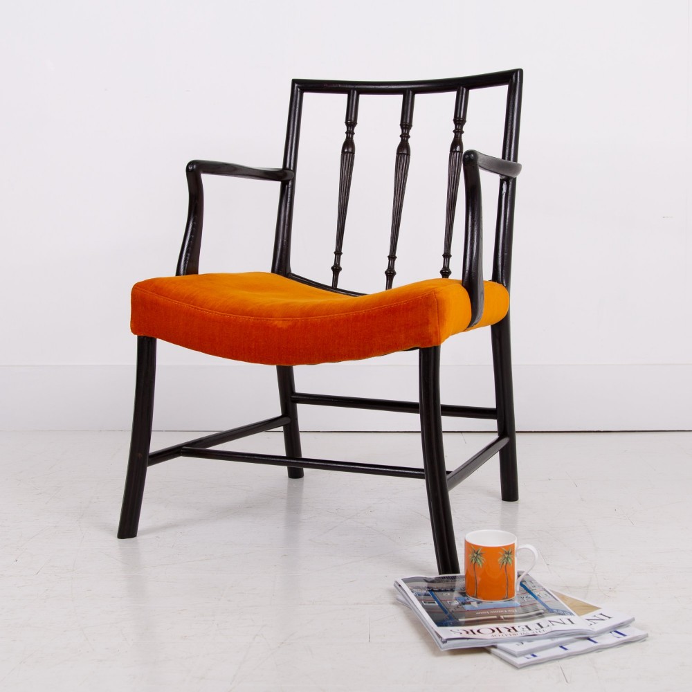 An ebonised wooden Cockpen armchair featuring a turned spindled backrest, curved armrests, and an orange velvet seat.