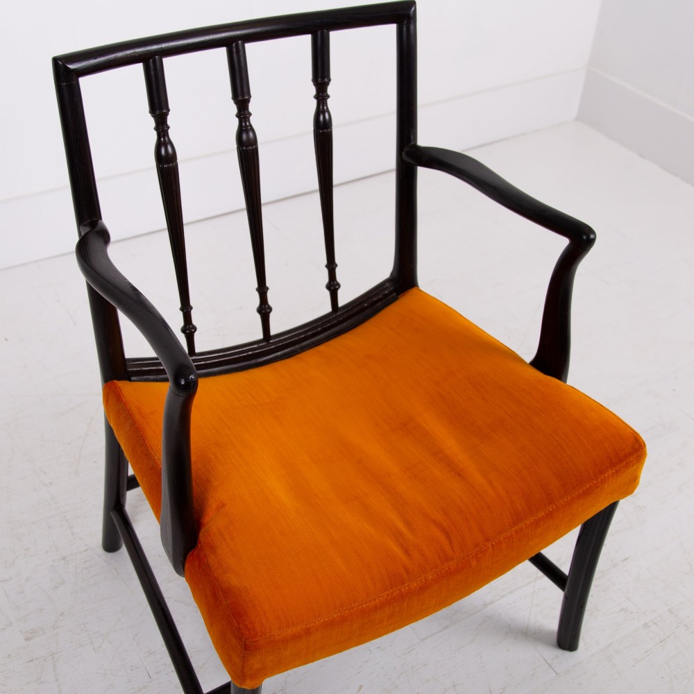 An ebonised wooden Cockpen armchair featuring a turned spindled backrest, curved armrests, and an orange velvet seat. View III