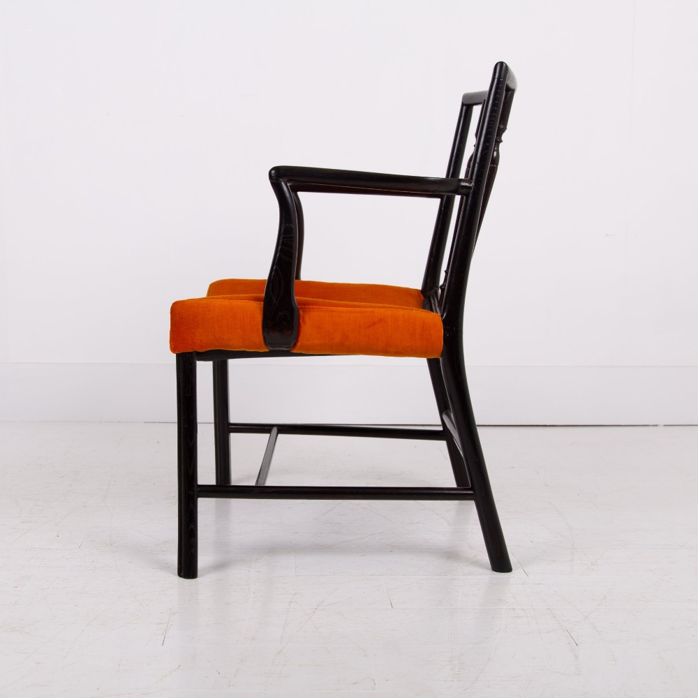 An ebonised wooden Cockpen armchair featuring a turned spindled backrest, curved armrests, and an orange velvet seat. View V