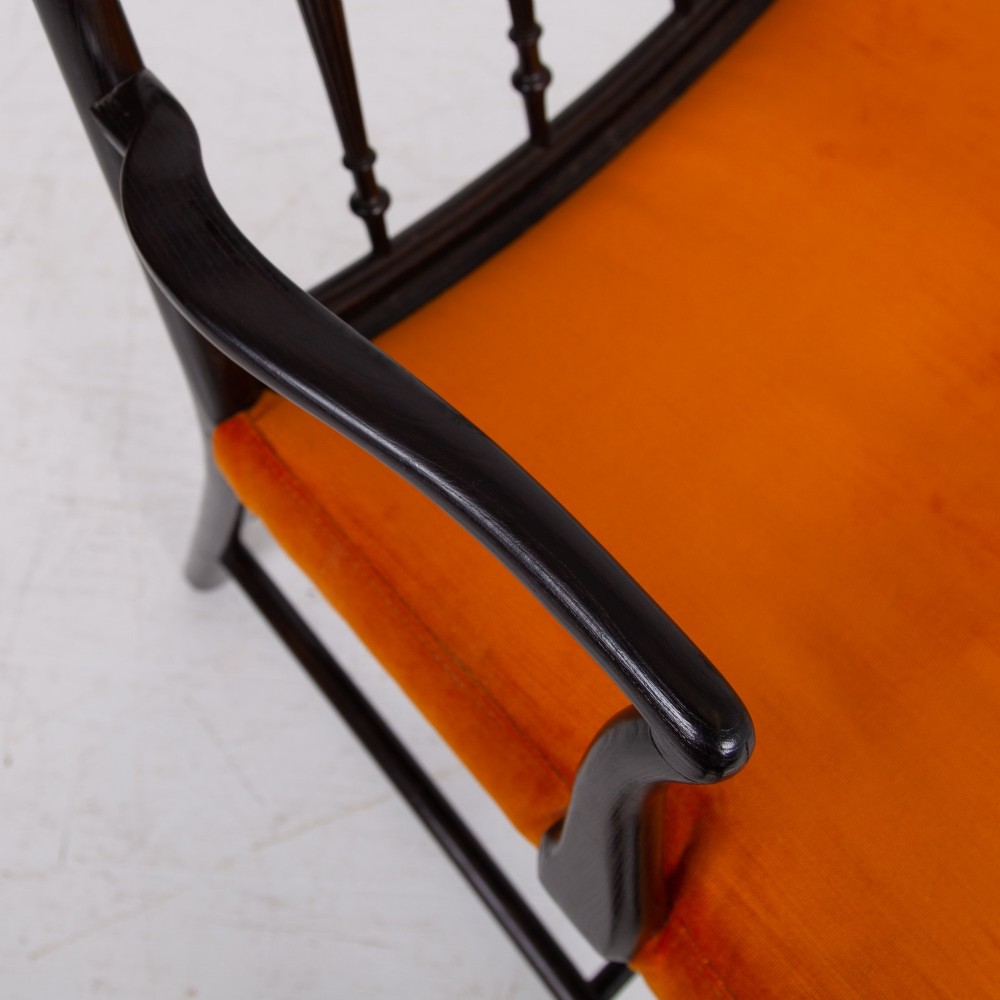 An ebonised wooden Cockpen armchair featuring a turned spindled backrest, curved armrests, and an orange velvet seat. View VIII