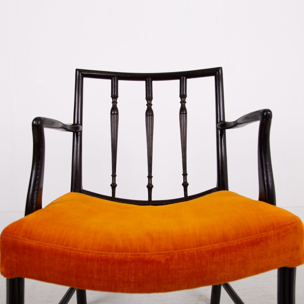 An ebonised wooden Cockpen armchair featuring a turned spindled backrest, curved armrests, and an orange velvet seat. View IX