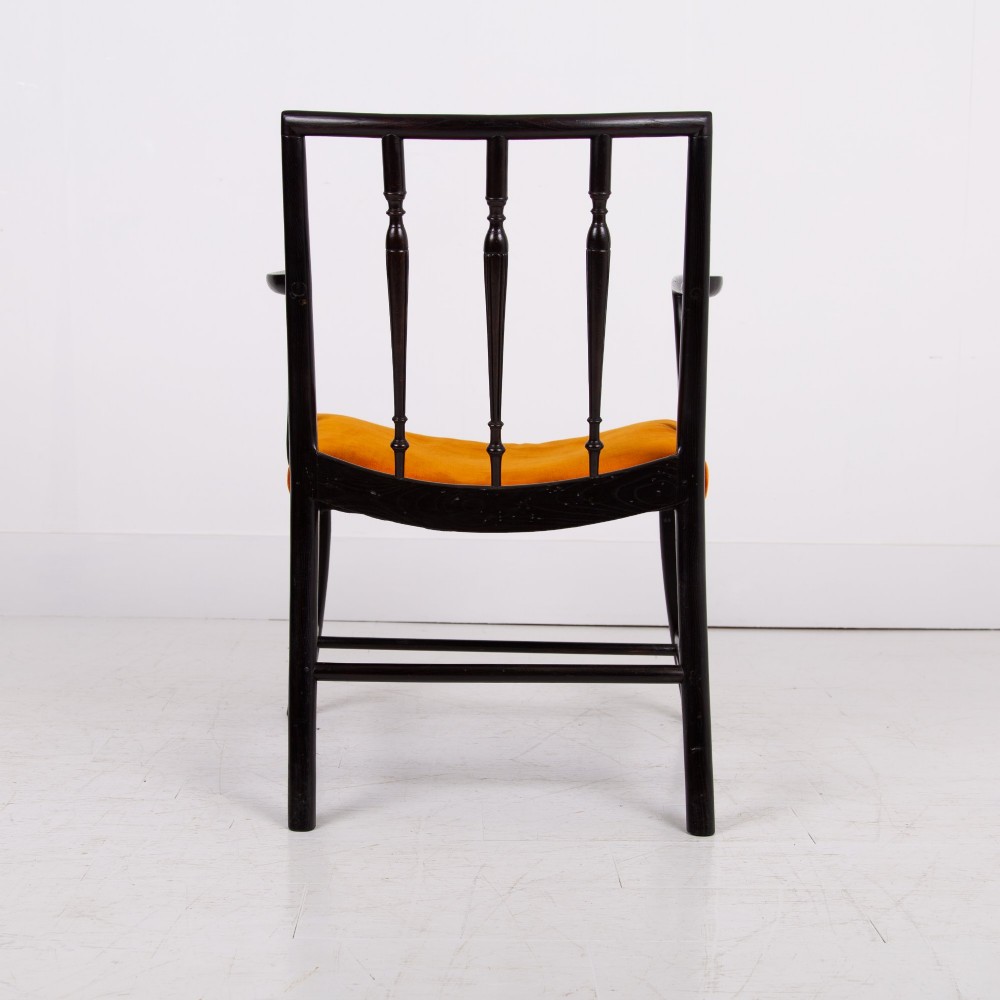 An ebonised wooden Cockpen armchair featuring a turned spindled backrest, curved armrests, and an orange velvet seat. View X