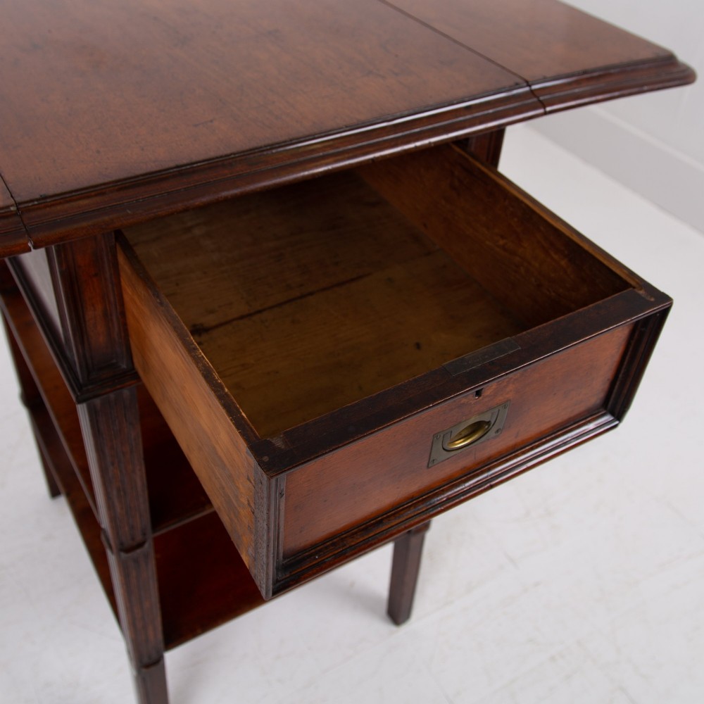 A late nineteenth-century dark mahogany drop-leaf table featuring a single top drawer with a brass pull, two lower open shelves, and fluted legs. View VI