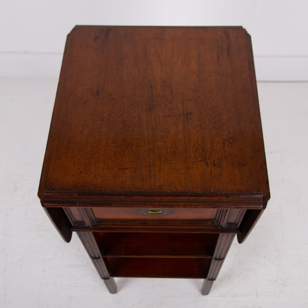 A late nineteenth-century dark mahogany drop-leaf table featuring a single top drawer with a brass pull, two lower open shelves, and fluted legs. View IX