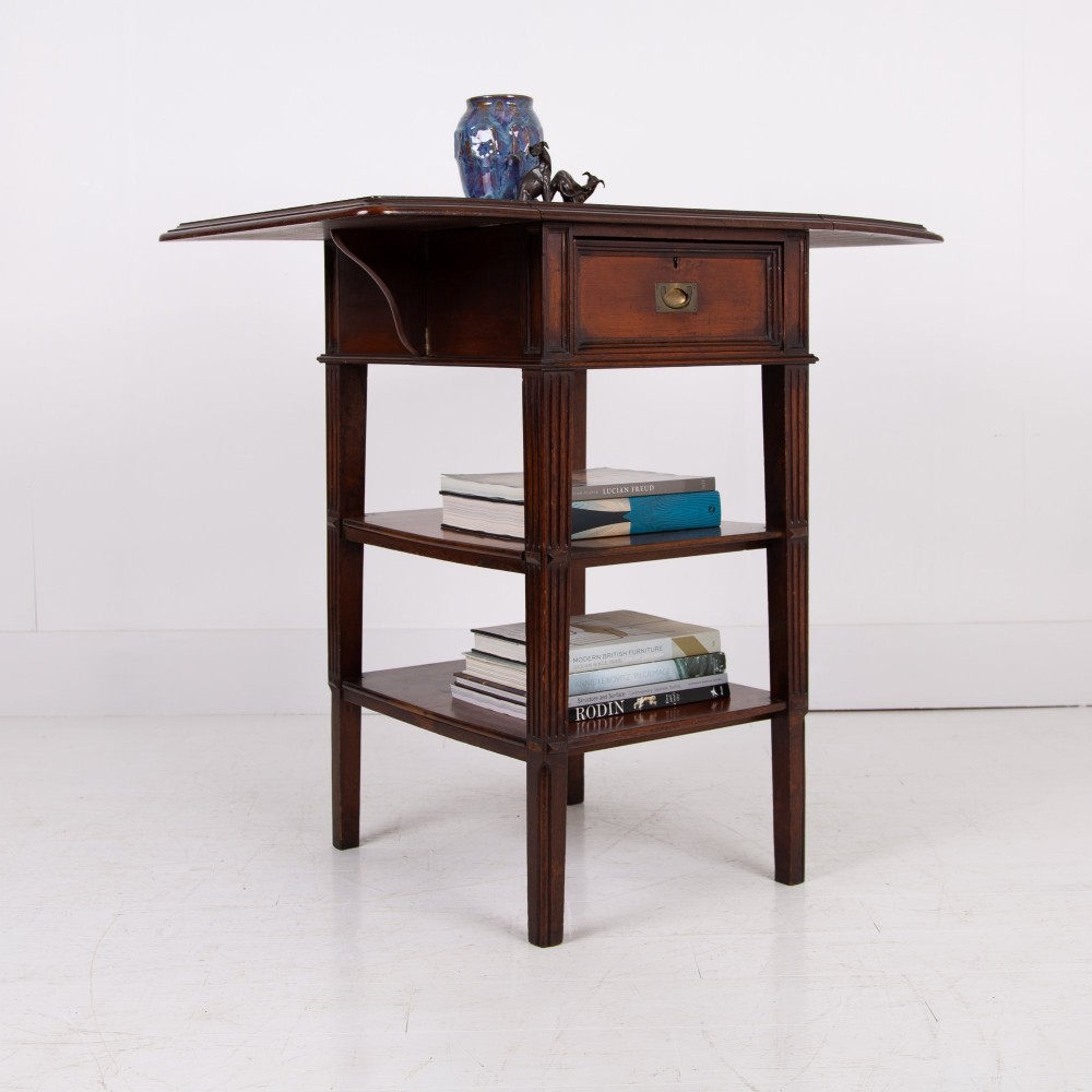 A late nineteenth-century dark mahogany drop-leaf table featuring a single top drawer with a brass pull, two lower open shelves, and fluted legs. View XIII