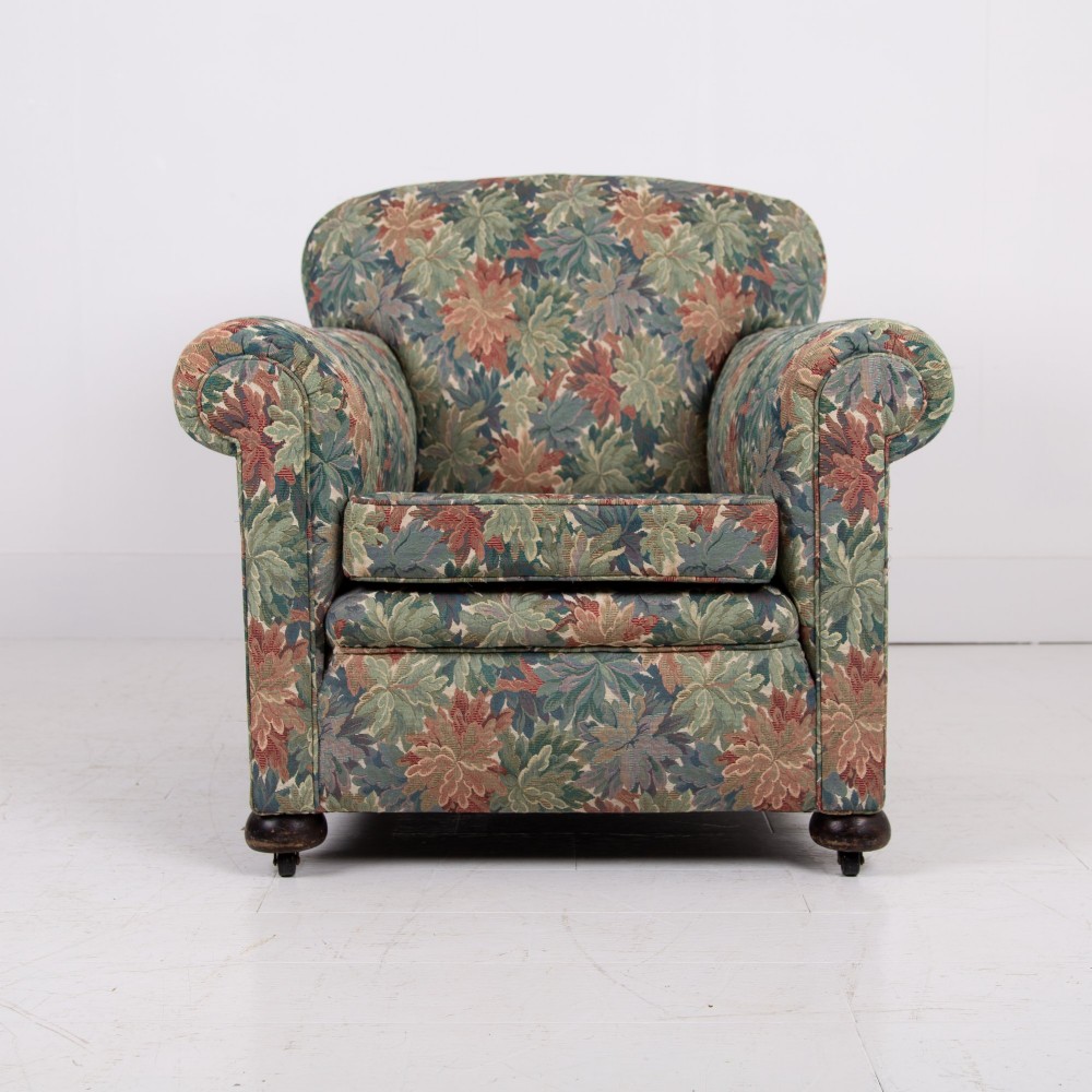 A pair of early 20th-century English upholstered armchairs featuring a multi-coloured botanical leaf pattern, deep seats, rolled arms, and turned feet on castors. View IV