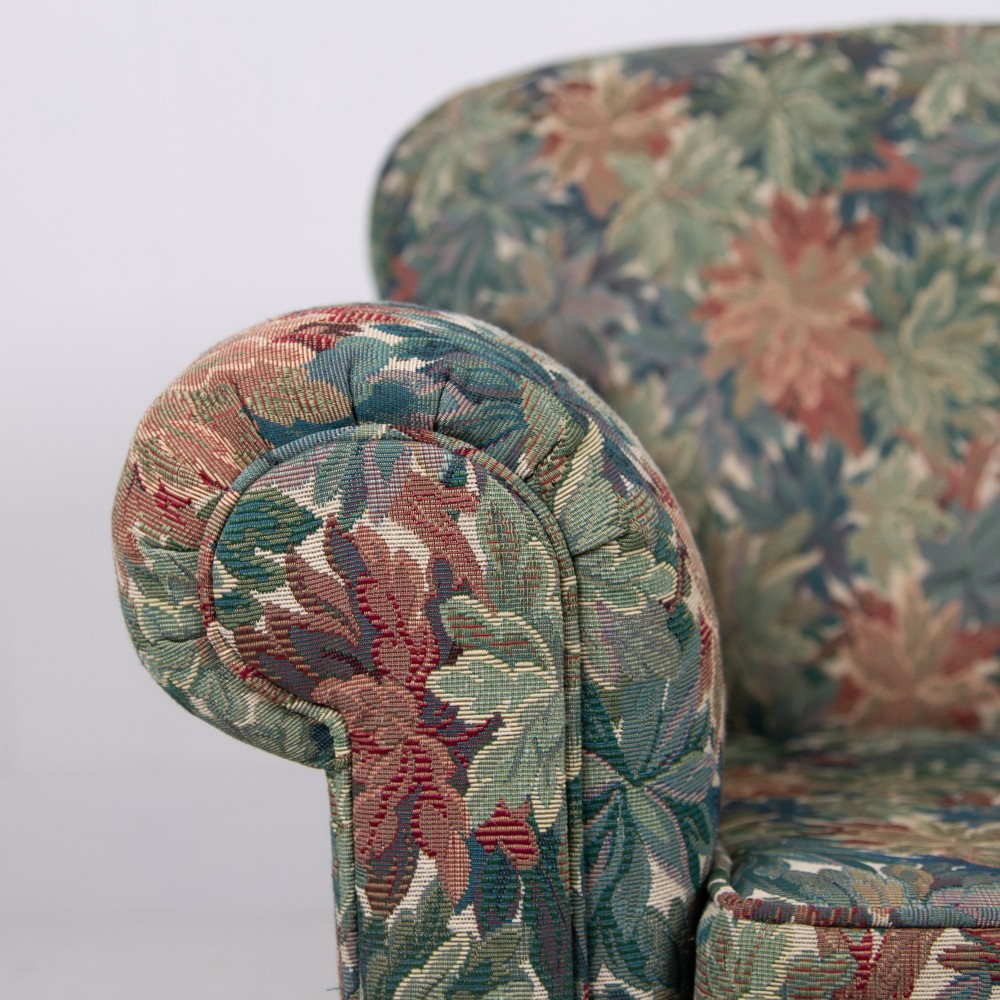 A pair of early 20th-century English upholstered armchairs featuring a multi-coloured botanical leaf pattern, deep seats, rolled arms, and turned feet on castors. View VII