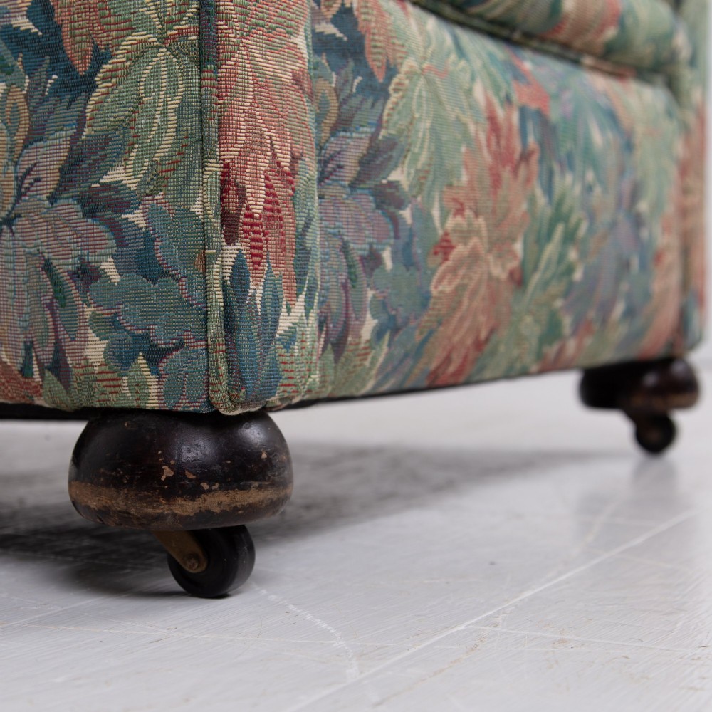 A pair of early 20th-century English upholstered armchairs featuring a multi-coloured botanical leaf pattern, deep seats, rolled arms, and turned feet on castors. View XIII