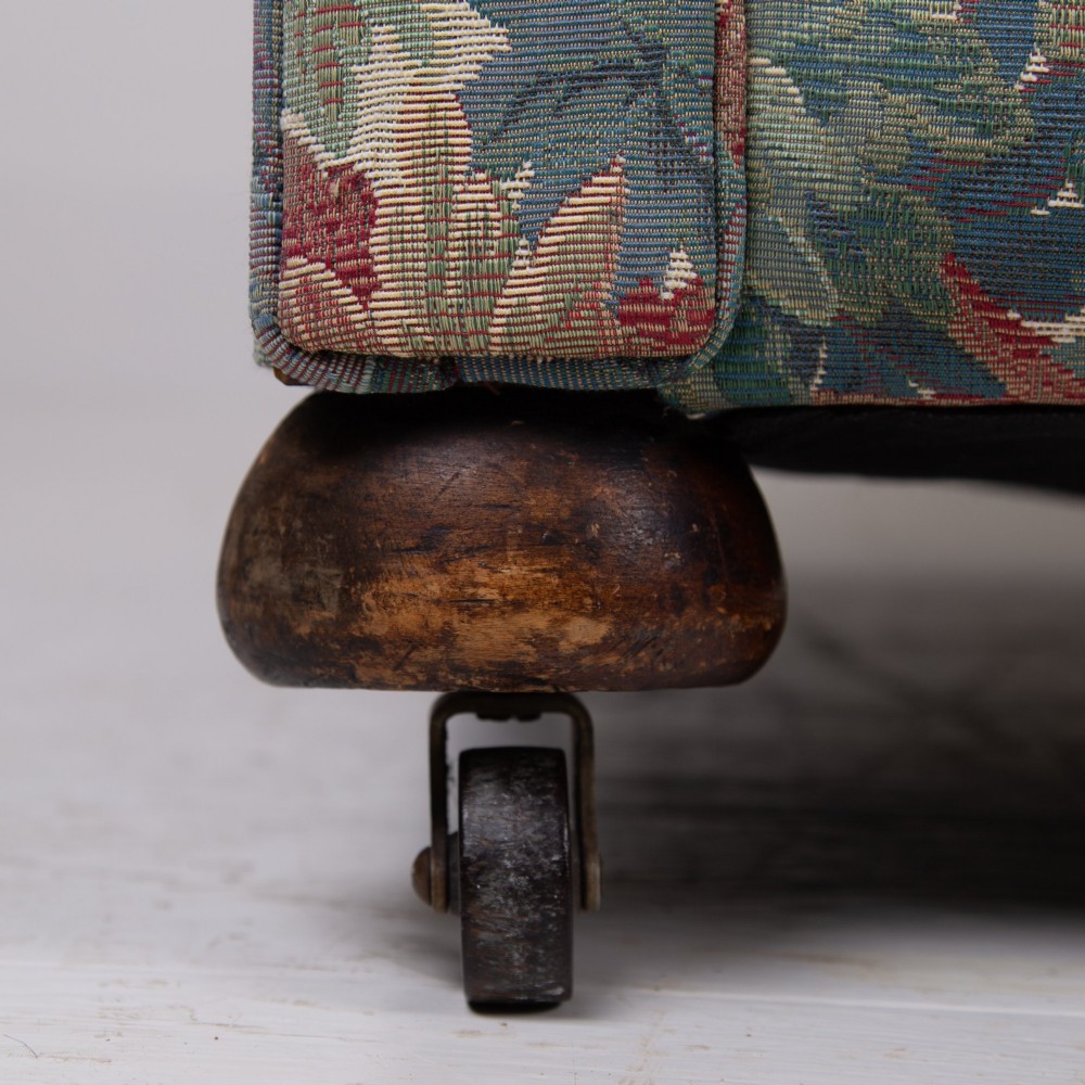 An Edwardian two-seater sofa upholstered in a multi-coloured leaf tapestry fabric with rolled arms and turned timber legs on casters. View VII