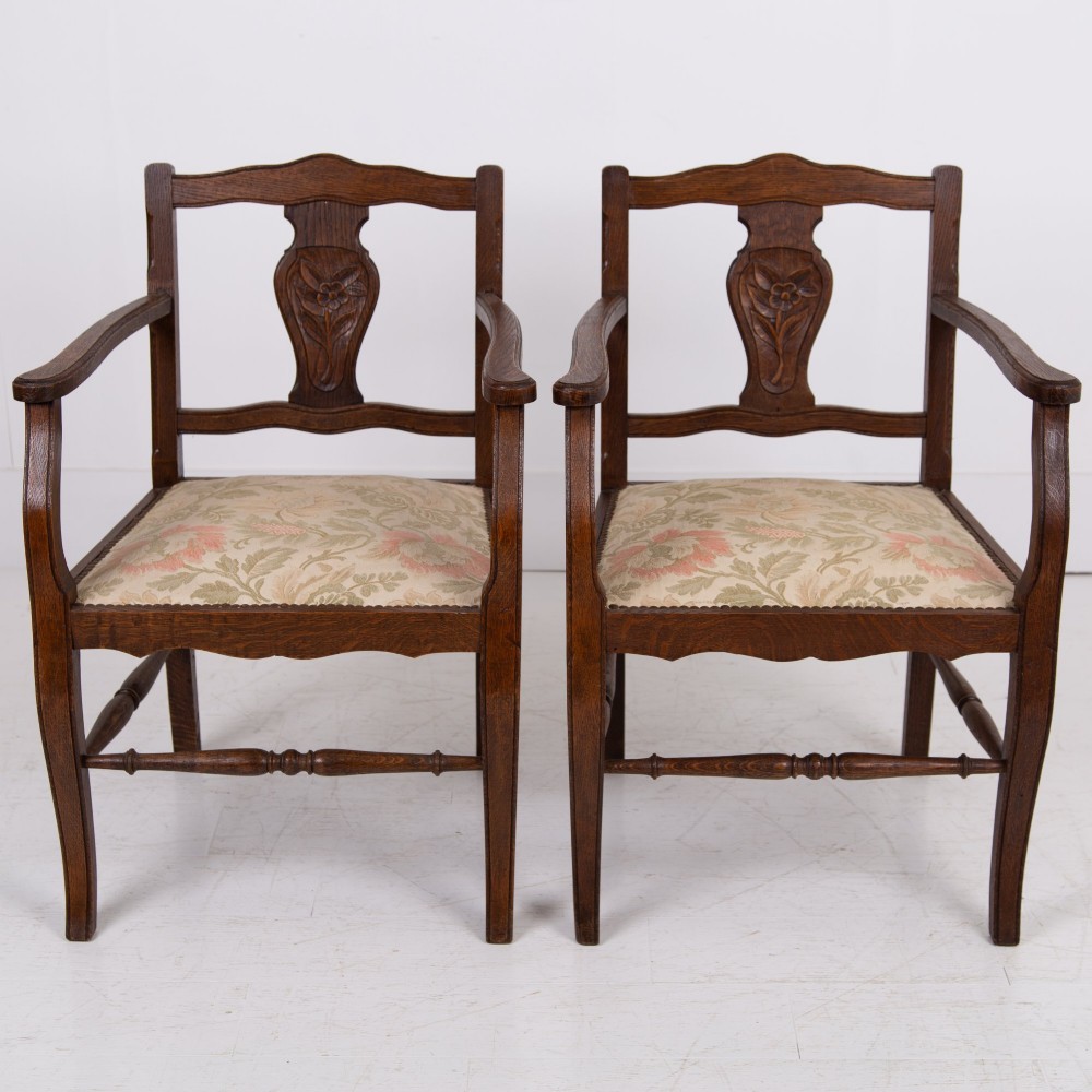 A pair of dark oak open armchairs featuring carved floral back splats, curved arms, turned stretchers, and light floral upholstered seats. View III