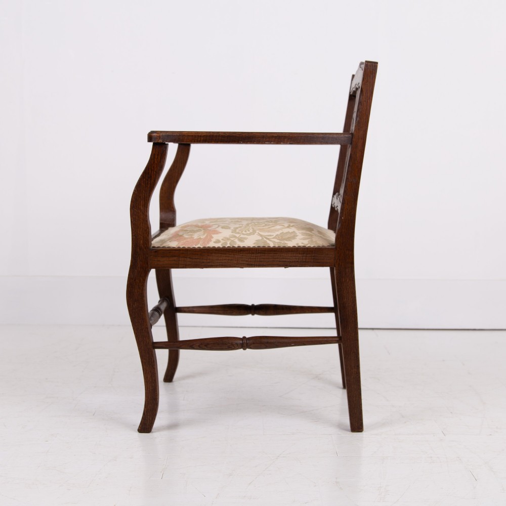 A pair of dark oak open armchairs featuring carved floral back splats, curved arms, turned stretchers, and light floral upholstered seats. View VI