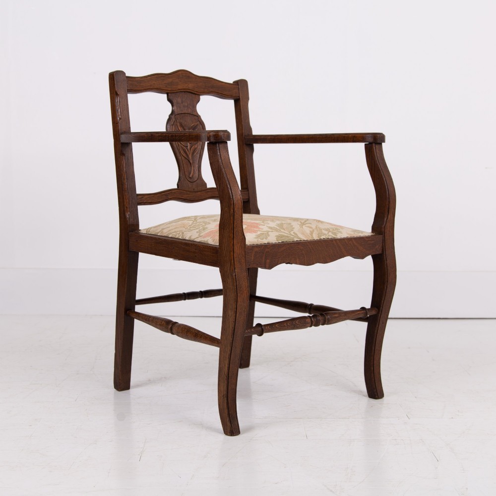 A pair of dark oak open armchairs featuring carved floral back splats, curved arms, turned stretchers, and light floral upholstered seats. View VII