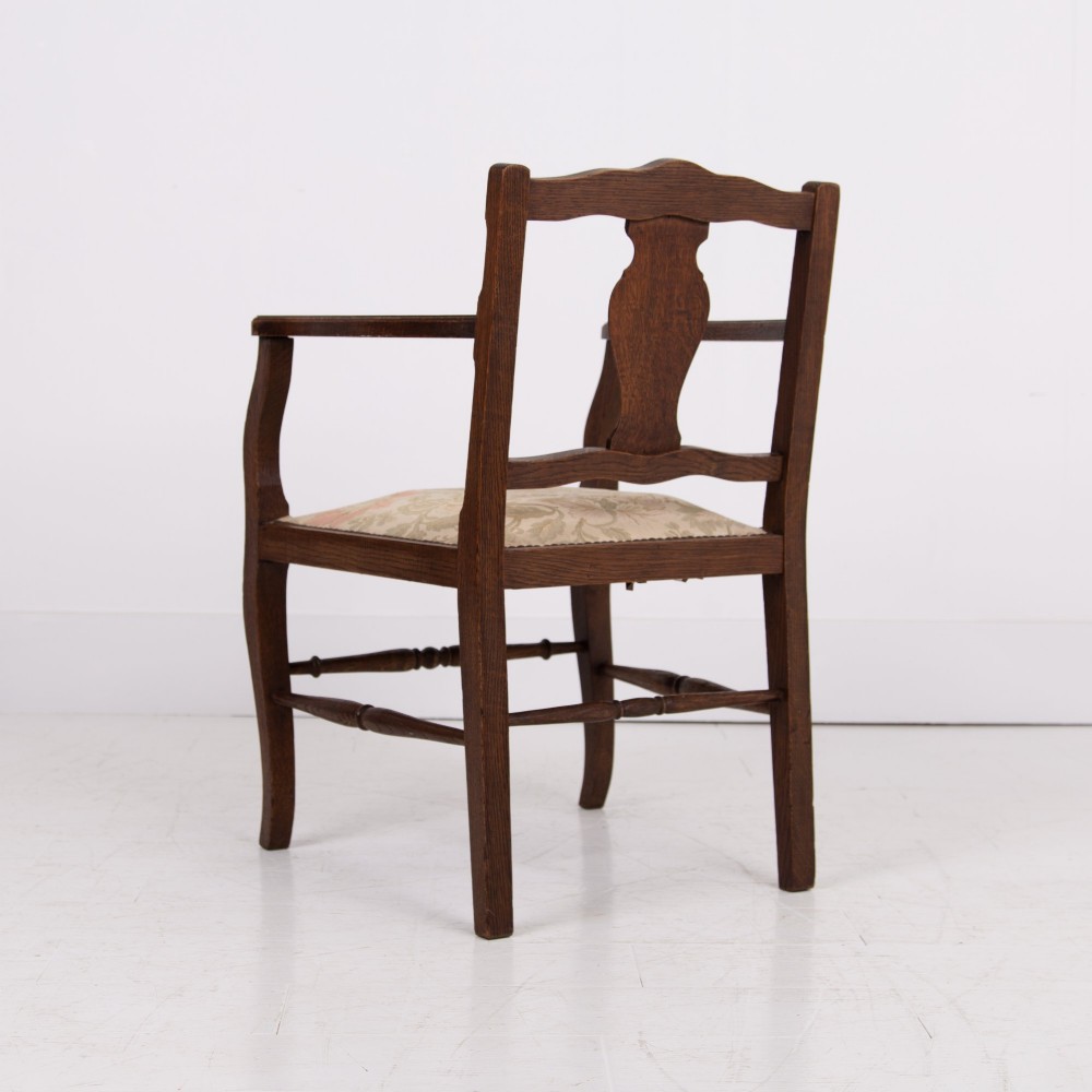 A pair of dark oak open armchairs featuring carved floral back splats, curved arms, turned stretchers, and light floral upholstered seats. View VIII