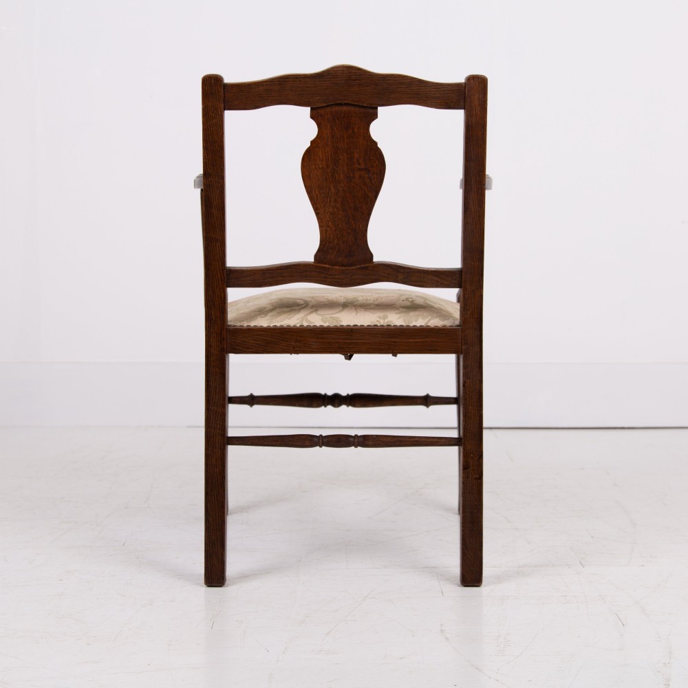 A pair of dark oak open armchairs featuring carved floral back splats, curved arms, turned stretchers, and light floral upholstered seats. View IX
