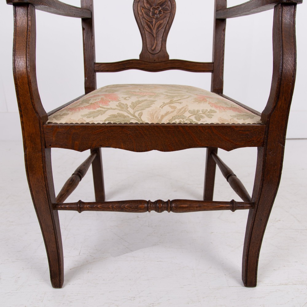 A pair of dark oak open armchairs featuring carved floral back splats, curved arms, turned stretchers, and light floral upholstered seats. View XI