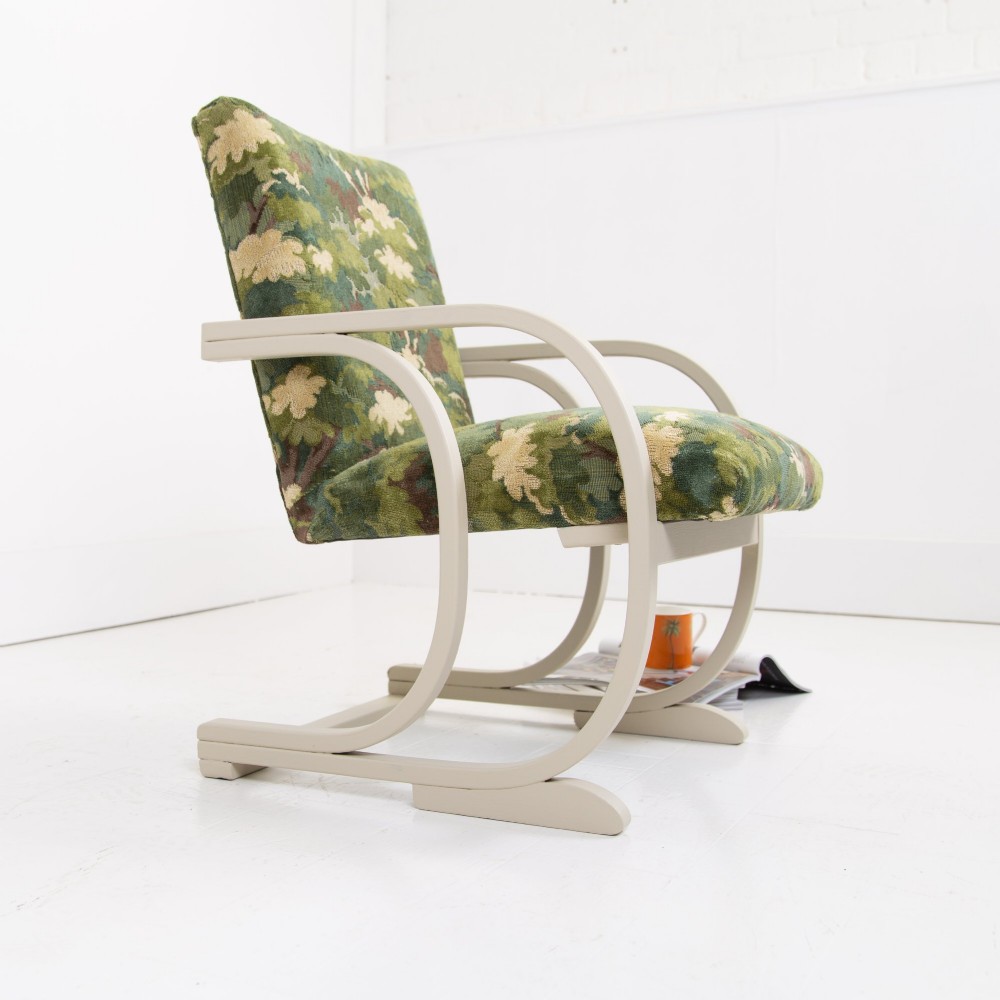 An Art Deco armchair featuring curved off-white painted bentwood arms and frame with green foliage pattern fabric upholstery on the seat and back. View II