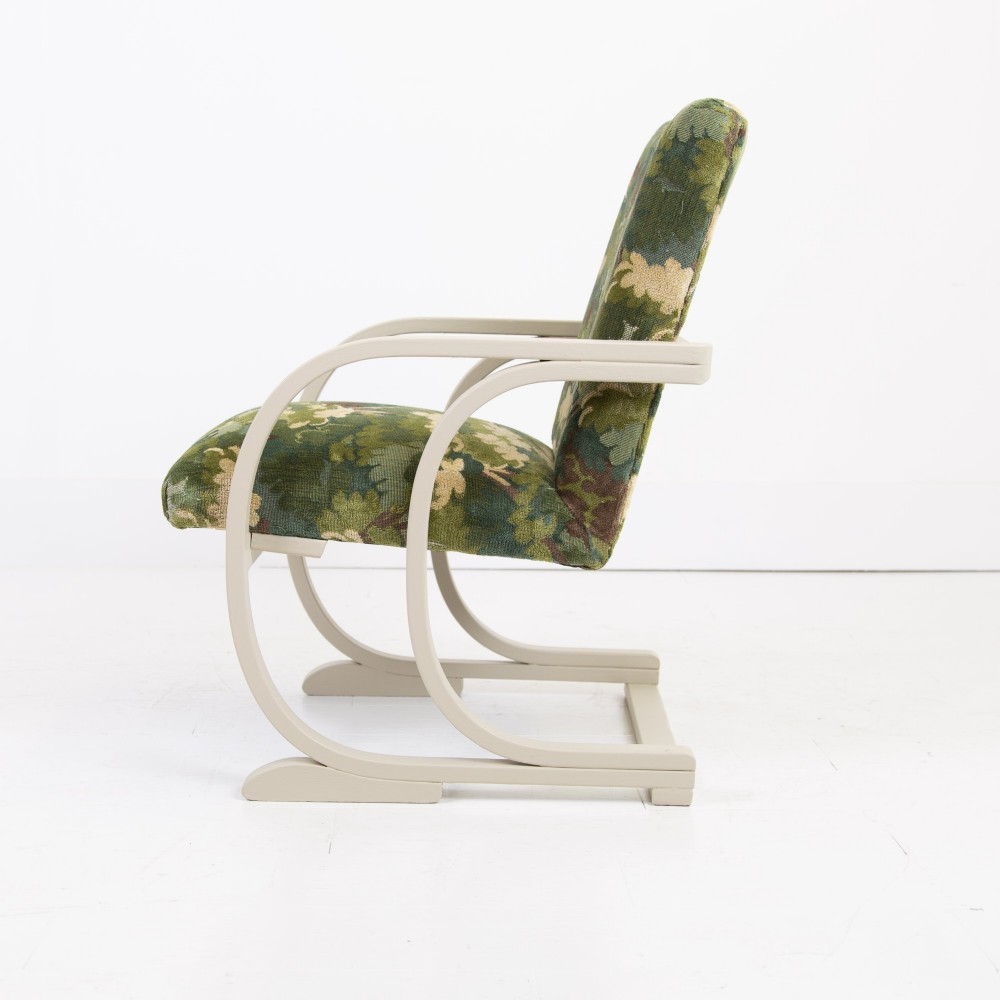 An Art Deco armchair featuring curved off-white painted bentwood arms and frame with green foliage pattern fabric upholstery on the seat and back. View IV