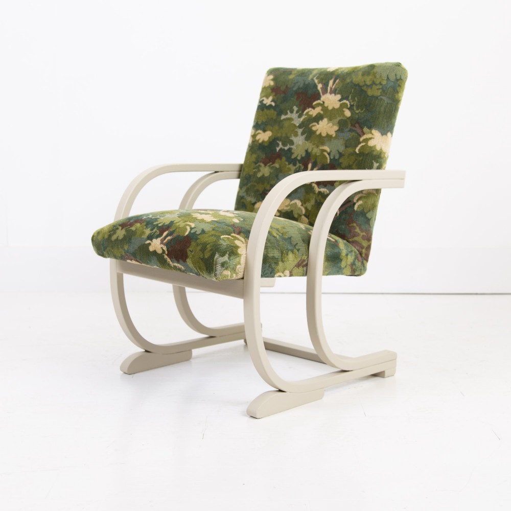 An Art Deco armchair featuring curved off-white painted bentwood arms and frame with green foliage pattern fabric upholstery on the seat and back. View V