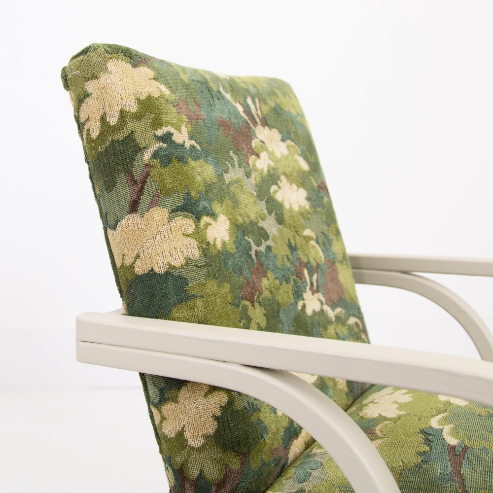 An Art Deco armchair featuring curved off-white painted bentwood arms and frame with green foliage pattern fabric upholstery on the seat and back. View VII