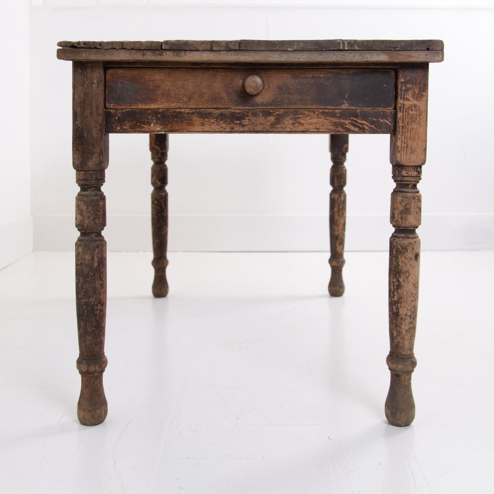 A late Victorian rustic wooden kitchen table featuring turned legs, a single drawer, and a distressed dark finish. View II