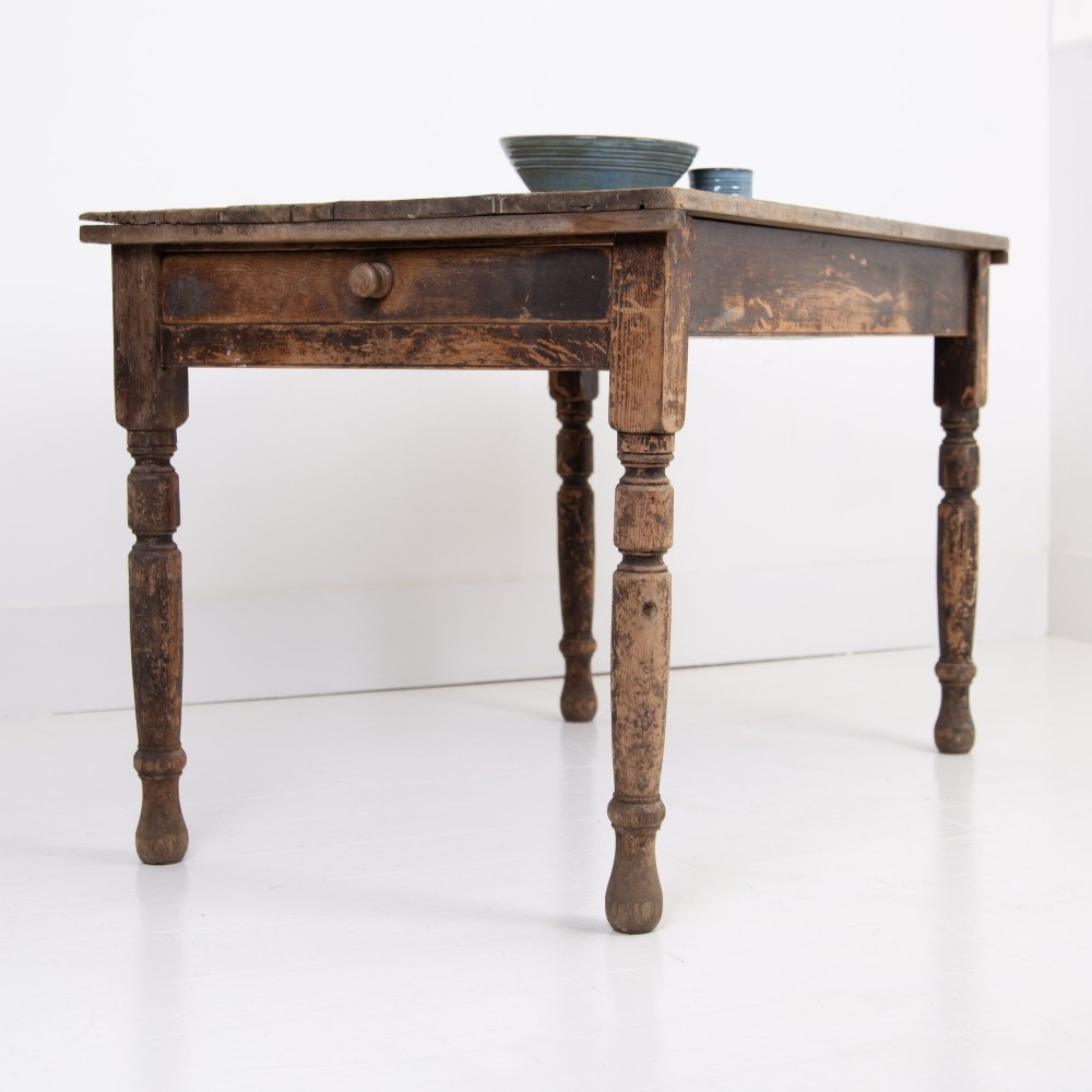 A late Victorian rustic wooden kitchen table featuring turned legs, a single drawer, and a distressed dark finish. View X