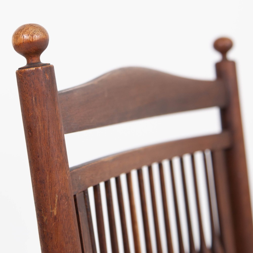 An antique Arts and Crafts wooden armchair featuring turned spindle backrest slats, sloped armrests, turned finials, and a hand-woven natural rush seat. View VI