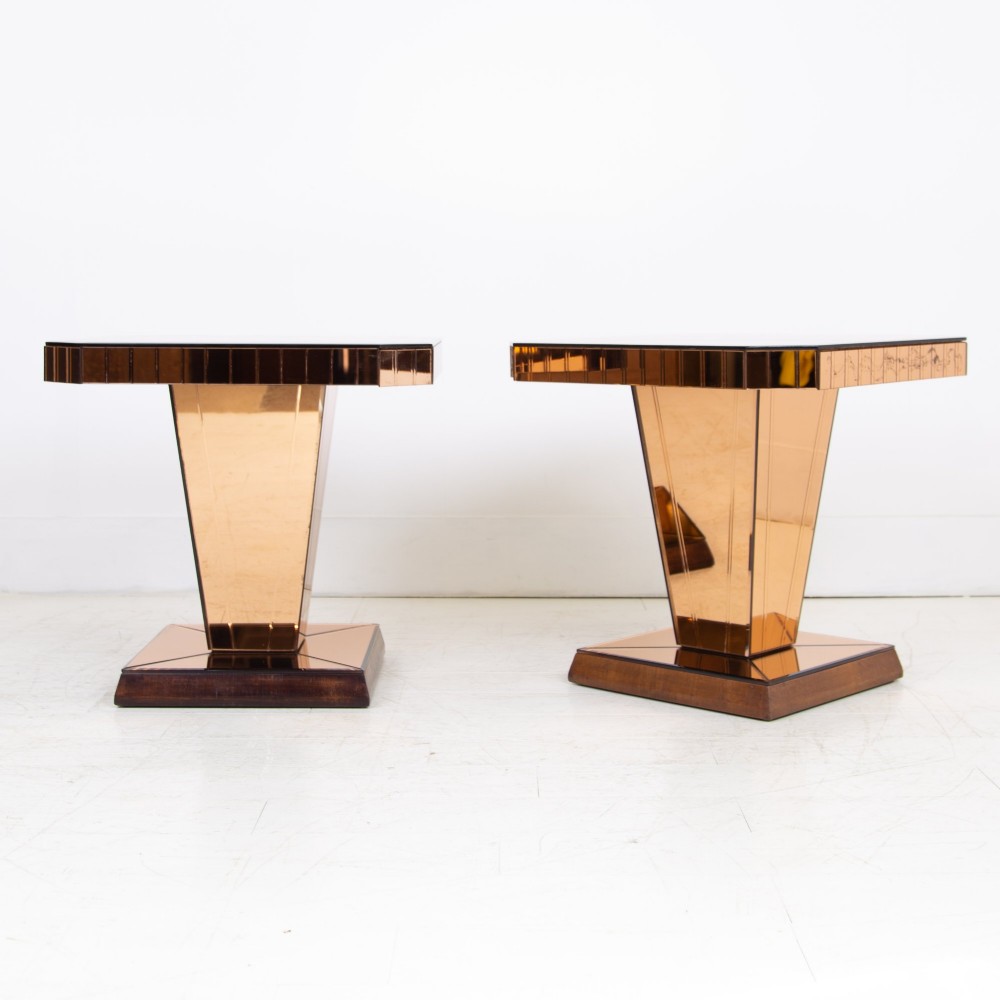 A pair of 1930s Art Deco side tables featuring peach-tinted mirrored tops, inverted pyramidal pedestal bases, and stepped square foundations.