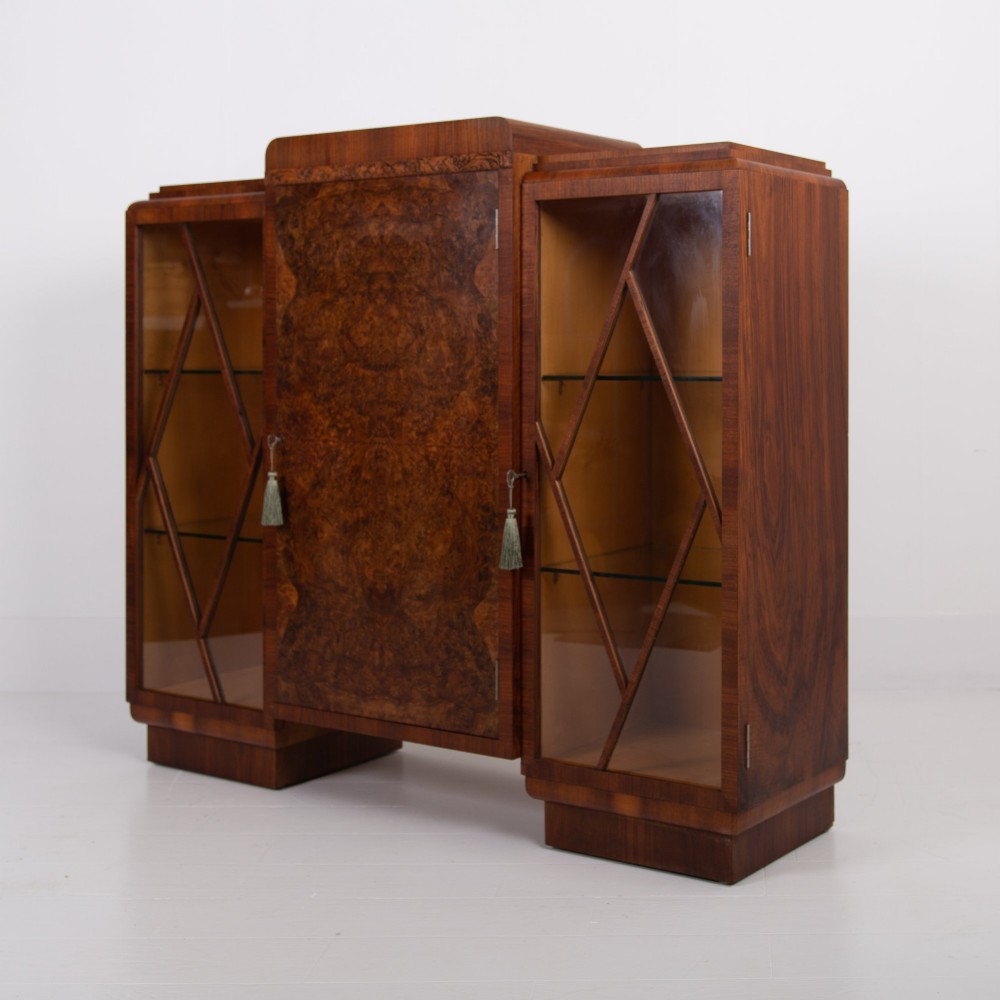 An Art Deco walnut display cabinet featuring a central burr walnut door flanked by two glazed doors with geometric diamond glazing bars.