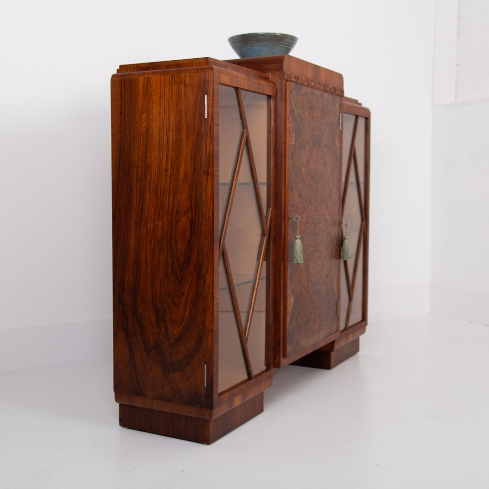 An Art Deco walnut display cabinet featuring a central burr walnut door flanked by two glazed doors with geometric diamond glazing bars. View VI