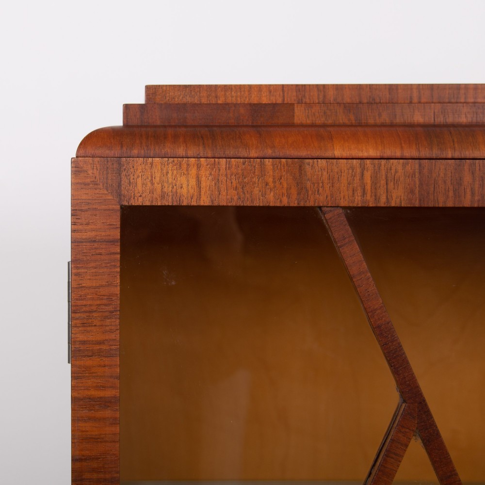 An Art Deco walnut display cabinet featuring a central burr walnut door flanked by two glazed doors with geometric diamond glazing bars. View VII